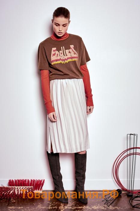 На девушке темно-оранжевая водолазка, коричневая свободная футболка с белой надписью, белая юбка плиссе длиной до середины колена, темно-серые замшевые ботфорты.